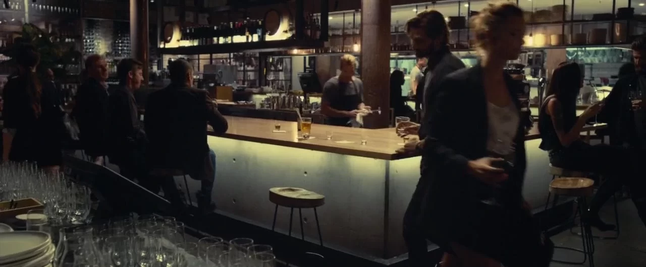 People sitting and standing around a dimly lit bar.