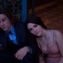 Two people sitting close in dim lighting.
